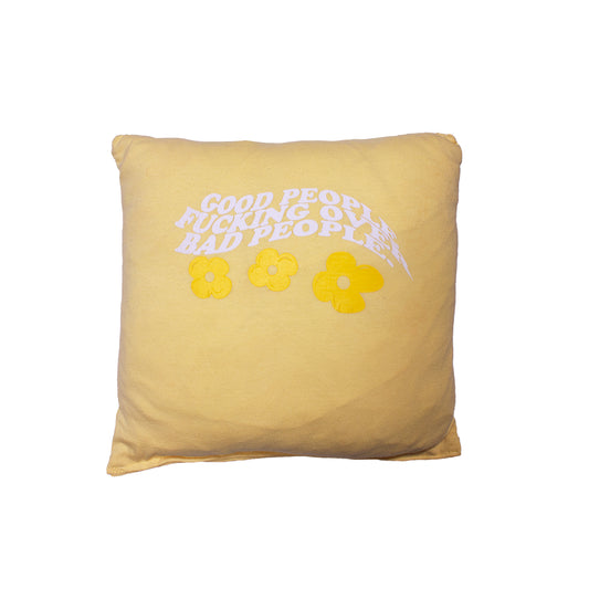 front of a yellow pillow with screen printed graphic that says "Good People Fucking Over Bad People" with yellow flowers